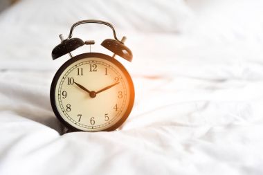 Çalar saat beyaz yatakta. Tatil ve anımsatıcı kavramı. Saat el noktasına saat 10 10 dakika zaman
