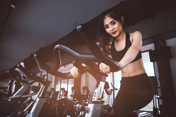 Asiática fitness mujer en bicicleta haciendo spinning en el gimnasio. Hermosa mujer joven hacer ejercicio en bicicleta de gimnasio. Concepto médico y saludable. Ejercicio y Cardio tema . — Foto de Stock