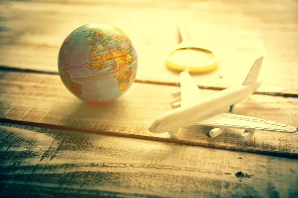 Avión pequeño y Globe y lupa vasos sobre fondo de textura de mesa de madera. Mundo mapa de viajes y vacaciones alrededor del mundo concepto — Foto de Stock
