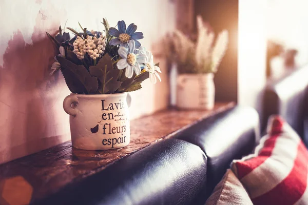 Vaso de flores com sofá e travesseiro no café e restaurante. Decoração de jardinagem e conceito de interiores. Vintage filme tom quente . — Fotografia de Stock