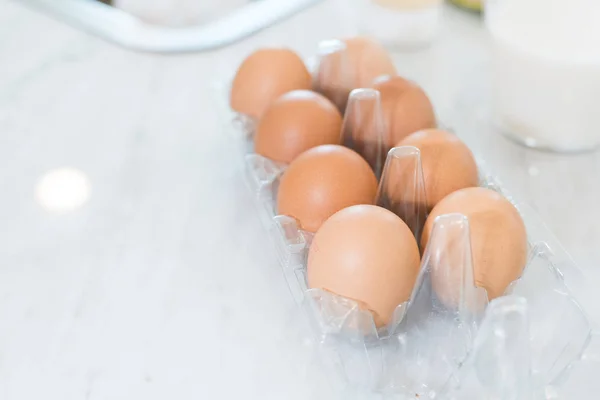 Κοντινό πλάνο του δεκάδες αυγά στον άσπρο πίνακα για να προετοιμάσει το μαγείρεμα στην κουζίνα. Επιδόρπιο συστατικά και η έννοια των τροφίμων. — Φωτογραφία Αρχείου