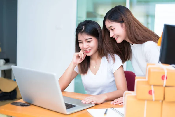 Two young freelancer Asian girl businesswomen private working at home office with laptop or computer with notebook on desk. packaging delivery online shopping and marketing service to customer — Stock Photo, Image