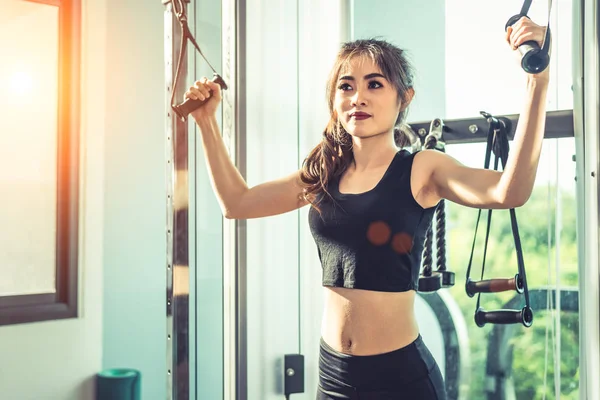 アジアの若い女性フィットネス ジム クロスで弾性ロープ演習を行います。筋力トレーニングと筋肉の美しさと健康の概念。スポーツ機器やスポーツ クラブの中心テーマ. — ストック写真