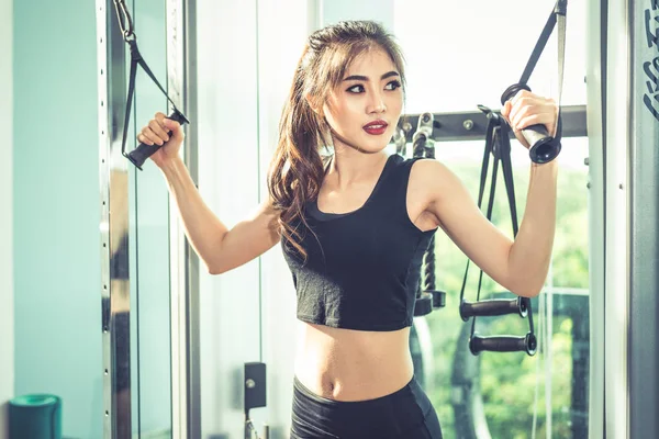 アジアの若い女性フィットネス ジム クロスで弾性ロープ演習を行います。筋力トレーニングと筋肉。美容と健康の概念。スポーツ機器やスポーツ クラブの中心テーマ. — ストック写真
