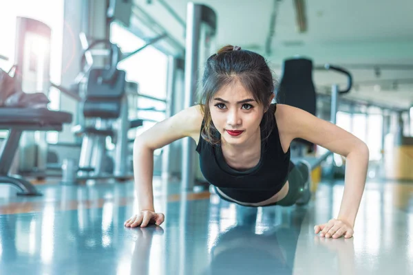 Mujer asiática chica de fitness hacer flexiones en el gimnasio de fitness. Salud y concepto saludable. Formación y Cuerpo construir el tema. Concepto de fuerza y belleza —  Fotos de Stock