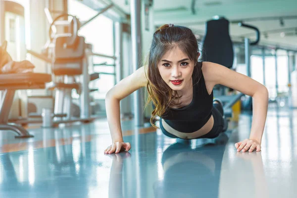 Mujer asiática chica de fitness hacer flexiones en el gimnasio de fitness. Salud y concepto saludable. Formación y Cuerpo construir el tema. Concepto de fuerza y belleza —  Fotos de Stock