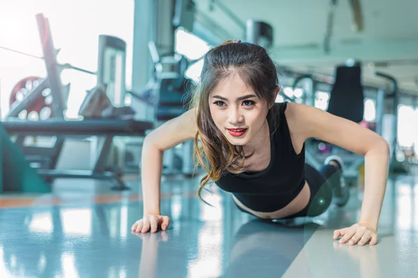 Mujer asiática chica de fitness hacer flexiones en el gimnasio de fitness. Salud y concepto saludable. Formación y Cuerpo construir el tema. Concepto de fuerza y belleza —  Fotos de Stock