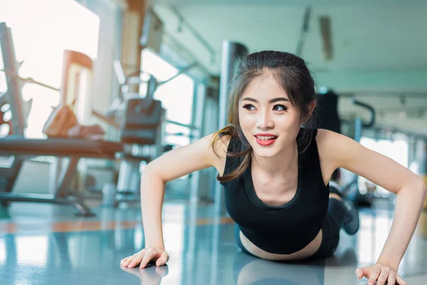 Азиатка фитнес-девушка отжимается в фитнес-зале. Здравоохранение и здоровая концепция. Тема тренировок и наращивания тела. Концепция силы и красоты — стоковое фото