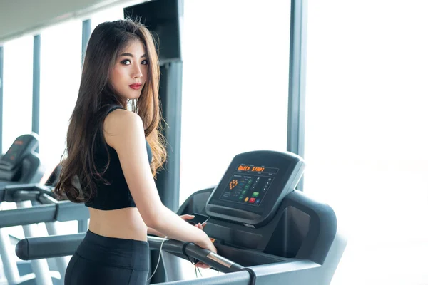 Asian sport woman walking or running on treadmill equipment in fitness workout gym. Sport and Beauty concept. Workout and Strength Training theme. Cardio and Diet theme. Woman portrait — Stock Photo, Image