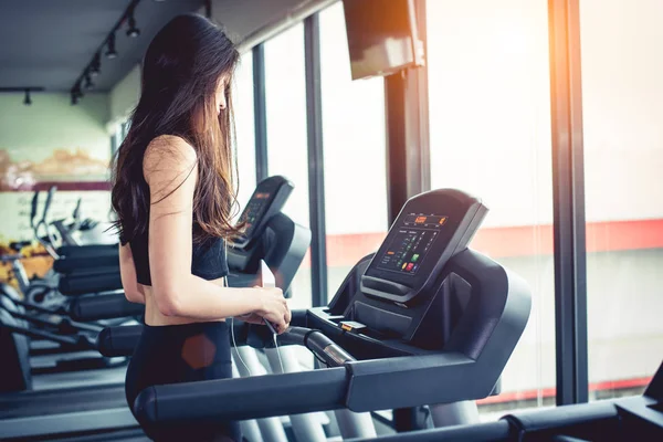 Aziatische vrouw met behulp van slimme telefoon wanneer training of sterkte opleiding op fitness sportschool op een loopband. Ontspannen en technologie concept. Sport oefening en gezondheidszorg thema. Happy en comfortabele sfeer. — Stockfoto