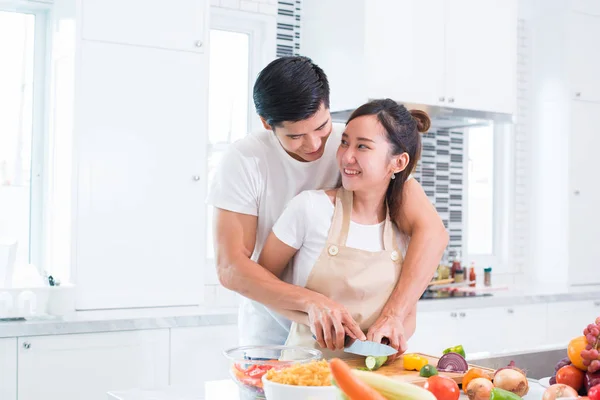 Ασιατικές εραστές ή ζευγάρι μαγείρεμα και κόψιμο λαχανικών στην κουζίνα. Άνδρας και γυναίκα ψάχνει άλλο στο σπίτι. Έννοιας διακοπές και μήνα του μέλιτος. Ημέρα του Αγίου Βαλεντίνου και το θέμα του γάμου — Φωτογραφία Αρχείου