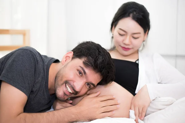 Father hearing his son or daughter kicking sound inside mother belly when sitting on lying on bed at home. Family and Lovers concept. Happy sweet home and wedding theme — Stock Photo, Image