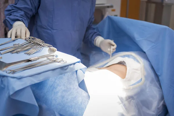 Médicos con herramientas en las manos haciendo cirugía en quirófano. Atención sanitaria y concepto hospitalario — Foto de Stock