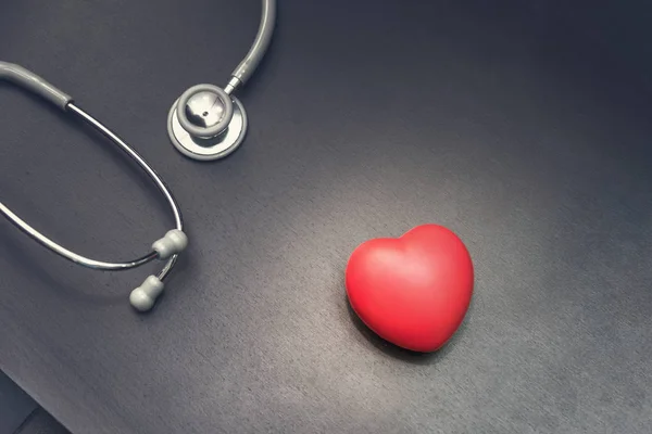 V pohledu shora, červené srdce s stetoskop zdravotnického zařízení na pozadí stolu lékaře. Lékařské a zdravotní péče koncept, téma nemocnice a pohotovost, tmavý tón pinterest a stolních jako proces. — Stock fotografie