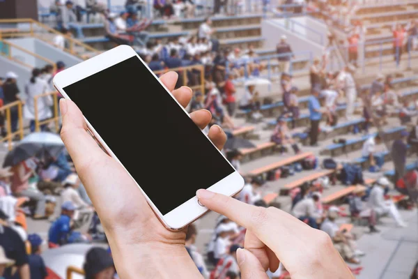 Perempuan memegang ponsel pintar dan tombol sentuh dengan tangan kosong layar untuk iklan, Stadion dan penonton latar belakang, Teknologi dan Olahraga konsep — Stok Foto