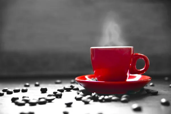 Café de la taza roja con el humo y el grano del café en la tabla de madera, concepto que bebe, color rojo selectivo — Foto de Stock