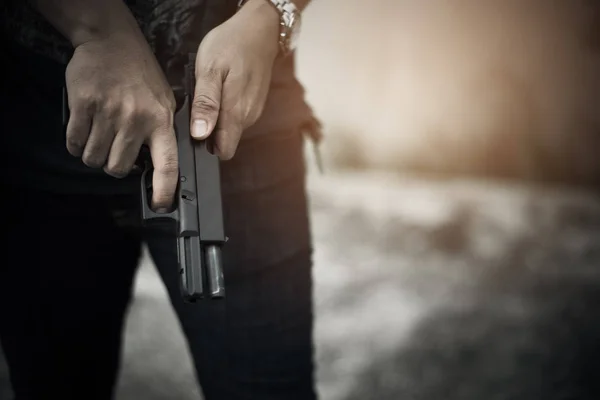 Robber holding gun for ready to murder steal moneys at abandoned building. Selective focus. criminality and social issues concept. Dark and low key tone tone pinterest and instragram like process. — Stock Photo, Image