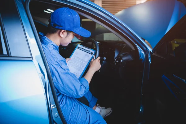 Mechaniker hält Klemmbrett und überprüft im Auto die Wartung — Stockfoto