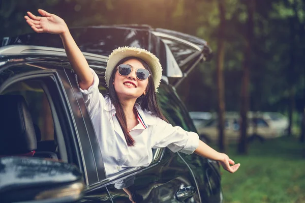 Glückliche Frau winkt Hand vor offenem Fenster Auto mit Wiese und — Stockfoto