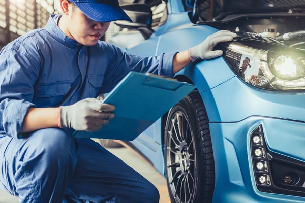 Asian car mechanic technician holding clipboard and checking to — 스톡 사진