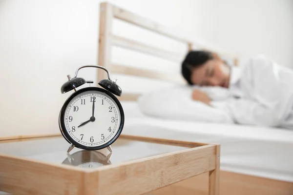 Крупним планом будильник зі сплячою жінкою в спальні. Час лінивця — стокове фото