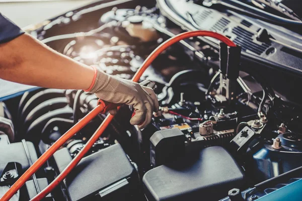 Automechanik drží bateriové elektrické žlabové kabely jumper an — Stock fotografie