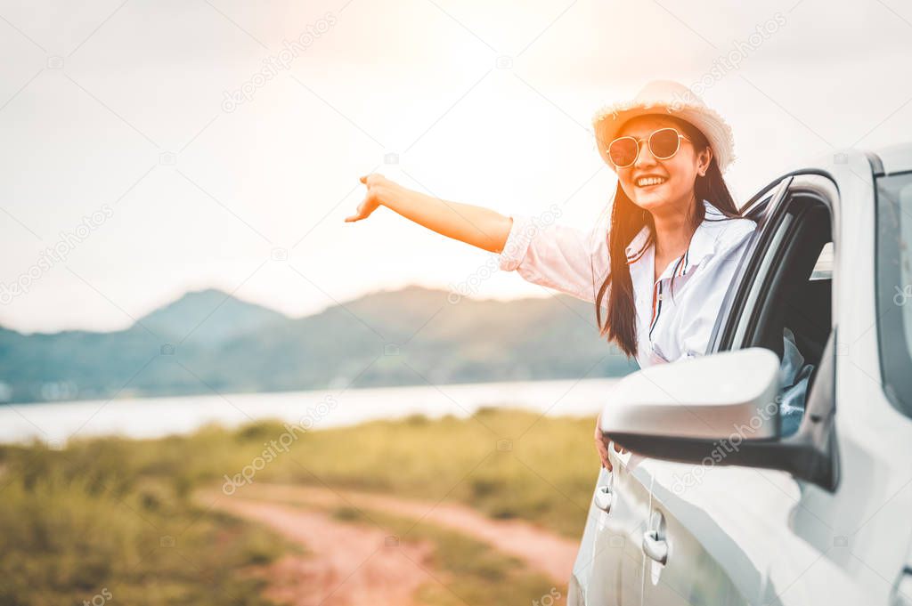Happy woman waving hand outside open window car with meadow and 