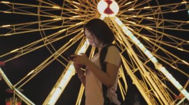 Mutlu Asyalı kadın dönme dolap geçmişiyle lunaparktaki arkadaşlarıyla telefon konuşmalarına bak. İnsanların yaşam tarzı ve eğlencesi. Seyahat ve tatil