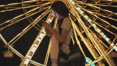 Mutlu Asyalı kadın dönme dolap geçmişiyle lunaparktaki arkadaşlarıyla telefon konuşmalarına bak. İnsanların yaşam tarzı ve eğlencesi. Seyahat ve tatil