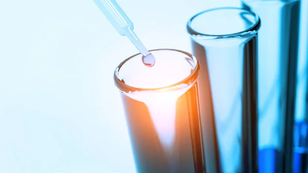 Close up pipette dropping blue solution sample into test tube — Stock Photo, Image