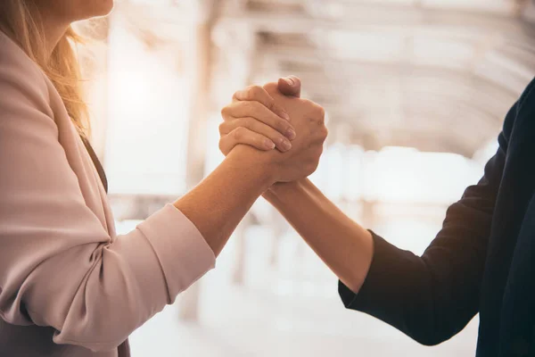 Business partnership meeting trust handshaking concept. Businesswomen doing arm wrestling. Successful business people contract promise for good confidence dealing with skyscraper building background