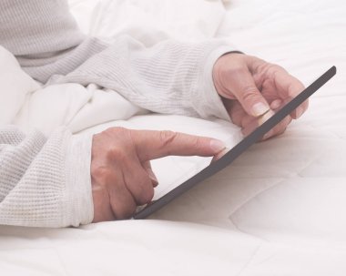 Yatakta bir kişi tarafından internet yayını için kullanılan bilgisayar yastığı ve 