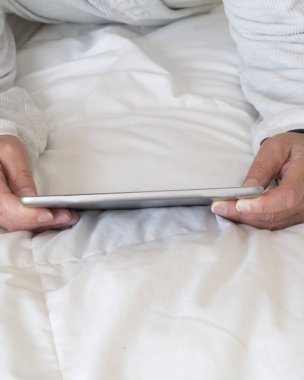 Yatakta bir kişi tarafından internet yayını ve bilgi için kullanılan bilgisayar yastığı .