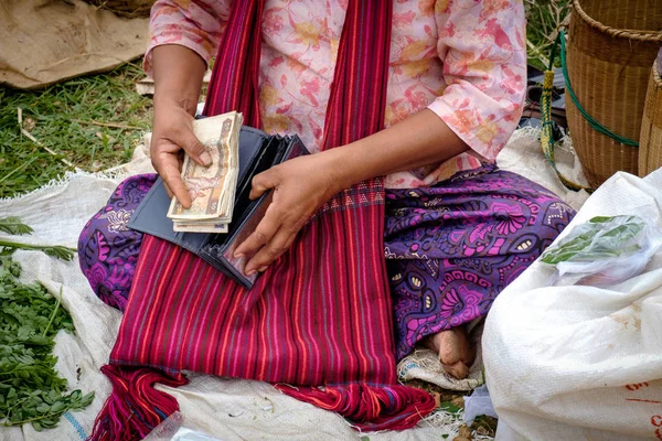Dettaglio di donna asiatica in vestiti colorati mettere soldi nella borsa — Foto Stock