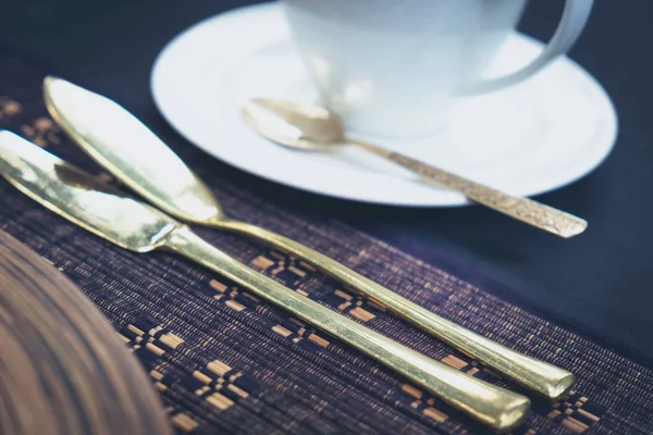 Détail des couverts dorés et d'une tasse posée sur une table — Photo