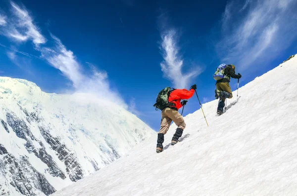 Dois trekkers da montanha na colina nevada íngreme com bac dramático do céu — Fotografia de Stock