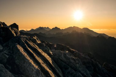 Yüksek Tatra 'daki güzel dağların ve bulutların üzerinde yükselen güneş