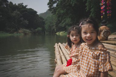 Göl kıyısındaki bir iskelede oturan iki kız.