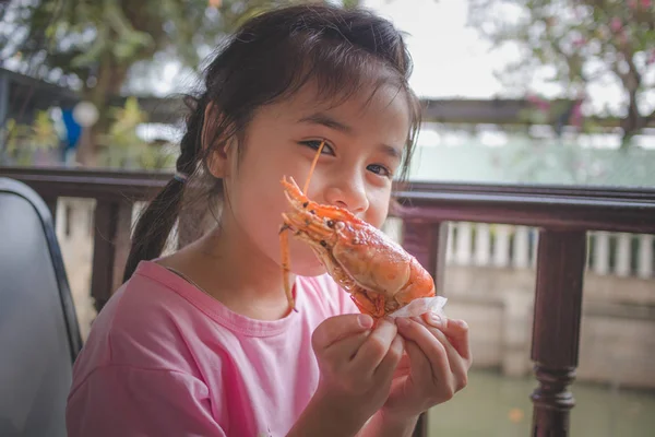 亚洲小女孩手里拿着一块烤虾仁 — 图库照片