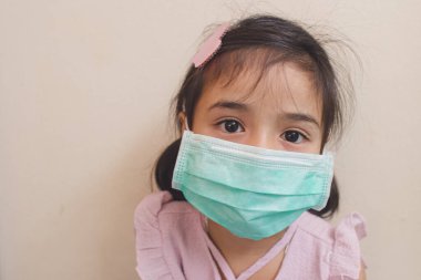 Coronavirus Covid-19 'u korumak için maske takan küçük kız. 