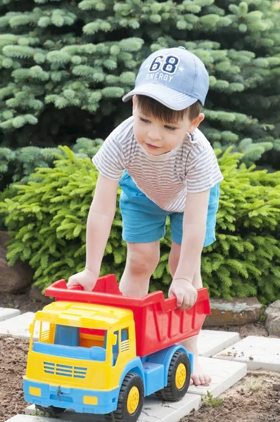 Un enfant joue sur l'herbe avec une grosse voiture jouet rouge — Photo