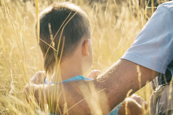 Baba ve oğul alanında oturmuş, baba hugs onun oğlu, tonda fotoğraf
