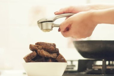 Kızarmış sarımsaklı kruton, siyah ekmek beyaz bir plaka üzerinde bir kadın eli sarımsak basın tutar.