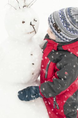 Bir çocuk bir kardan adam sokakta, bir çocuk bir kırmızı genel kışın sculpts