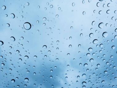 Mavi bir arka plan üzerine bir bardak su damlaları