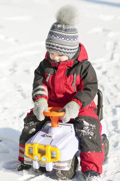 Küçük çocuk kırmızı kıyafeti mutlu bir şekilde kar oynarken