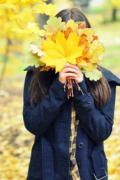 Kız yüzünü sarı sonbahar yaprakları, buket, sonbahar arkasında gizler — Stok fotoğraf