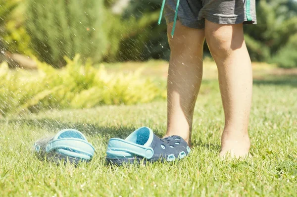 Детские ножки и детские синие тапочки на зеленой траве в саду, обувь для детей, концепция здорового образа жизни — стоковое фото