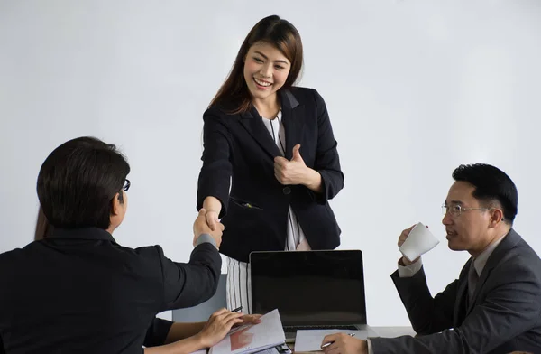 Дружелюбный улыбающийся бизнесмен и деловая женщина, пожимающие руку над офисным столом — стоковое фото