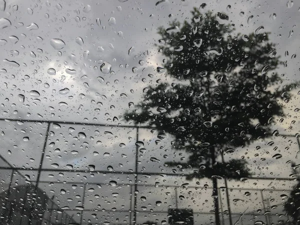Yağmurlu günlerde dış ayna ve bulanık arka plan görünümü ile araba penceresinde yağmur damlaları — Stok fotoğraf
